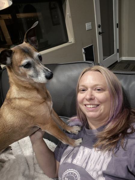 Allie relaxing on a couch with a tan senior dog standing beside her